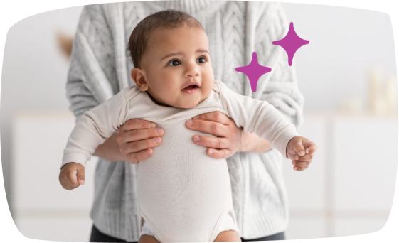 Un bebé sostenido por un adulto desde atrás